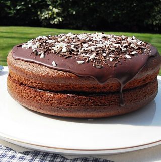 Olive Oil Chocolate Cake on a cake plate in garden.