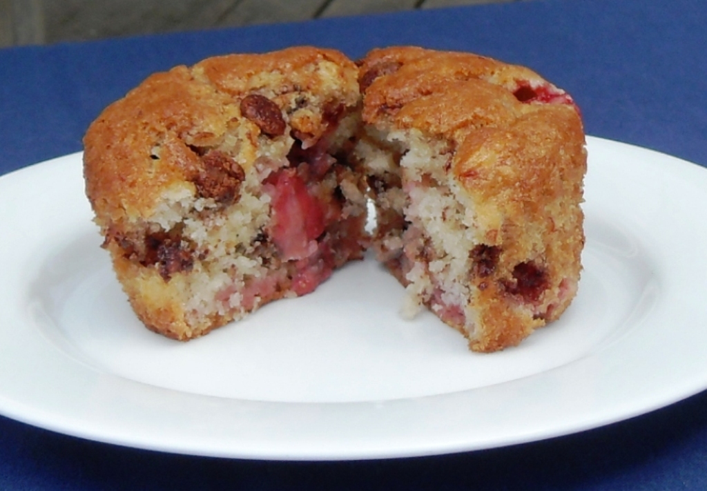 One Strawberry Banana Chocolate Chip Muffin on a plate cut in half.