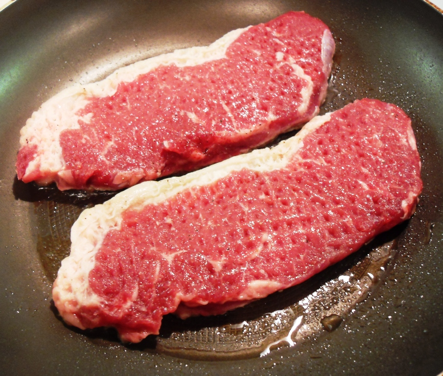 Sirloin steak in a frying pan.