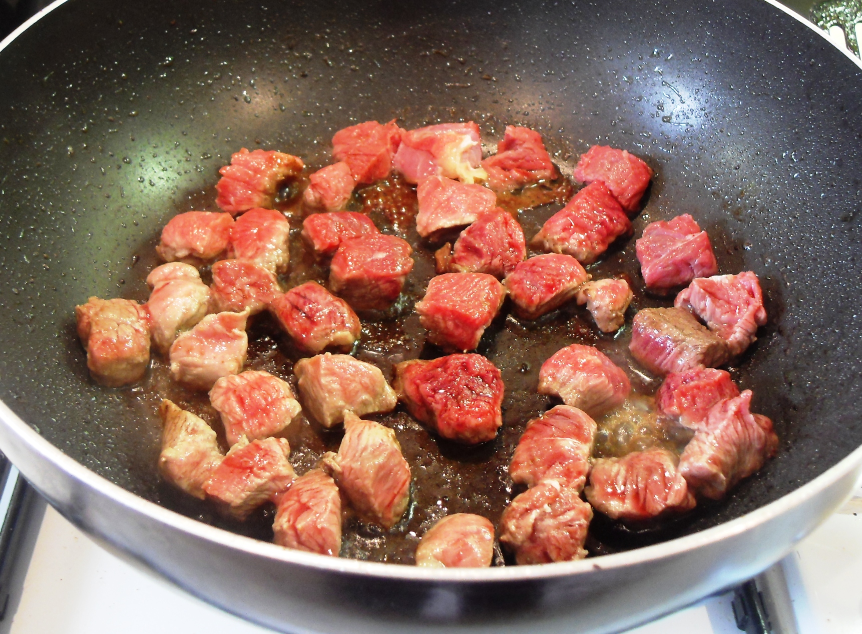 Beef being fried in a pan.