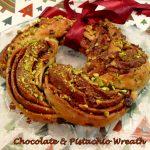 Chocolate & Pistachio Wreath with burgundy festive ribbon tied on.
