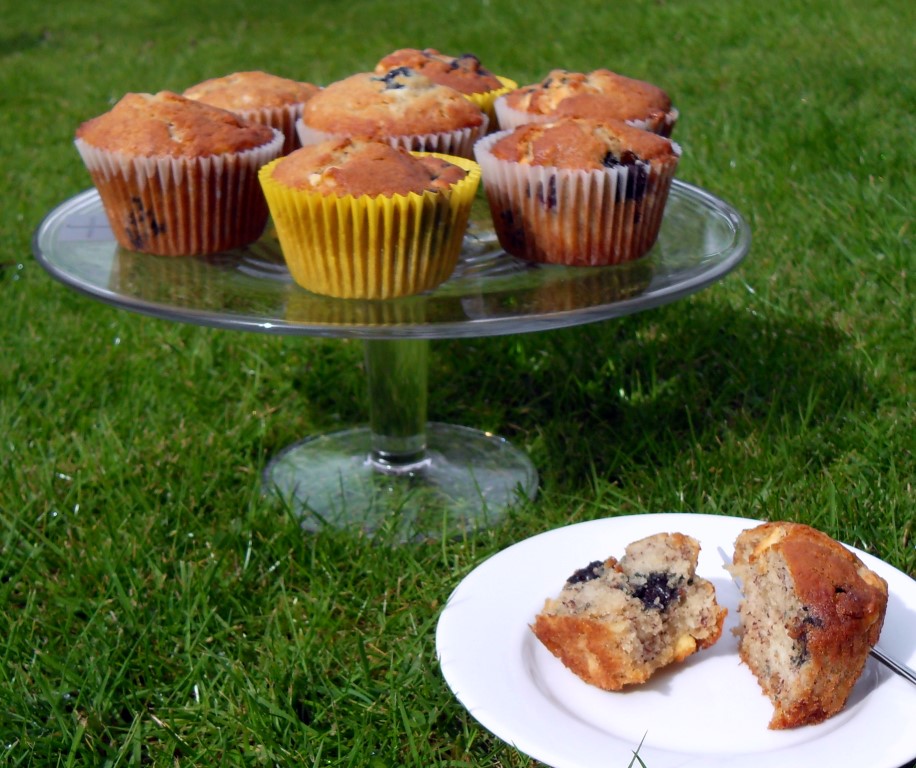 Blueberry, Banana & White Chocolate Muffins on a cake dish on a lawn.