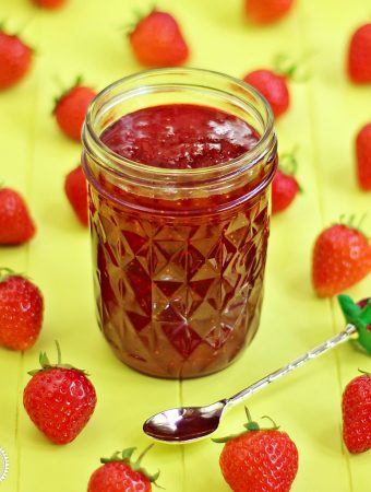 Quick One Punnet Strawberry Jam in jar with a teaspoon and scattered strawberries.