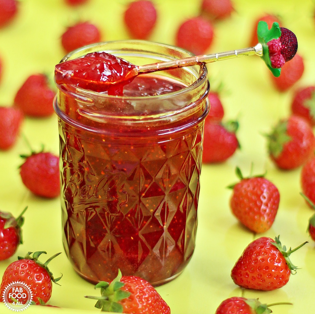 Quick One Punnet Strawberry Jam in jar with a teaspoon and scattered strawberries.