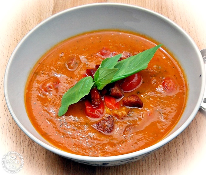 Roasted Tomato, Red Pepper & Chorizo Soup with basil leaf garnish.