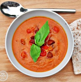 Roasted Tomato, Red Pepper & Chorizo Soup with basil leaf garnish.