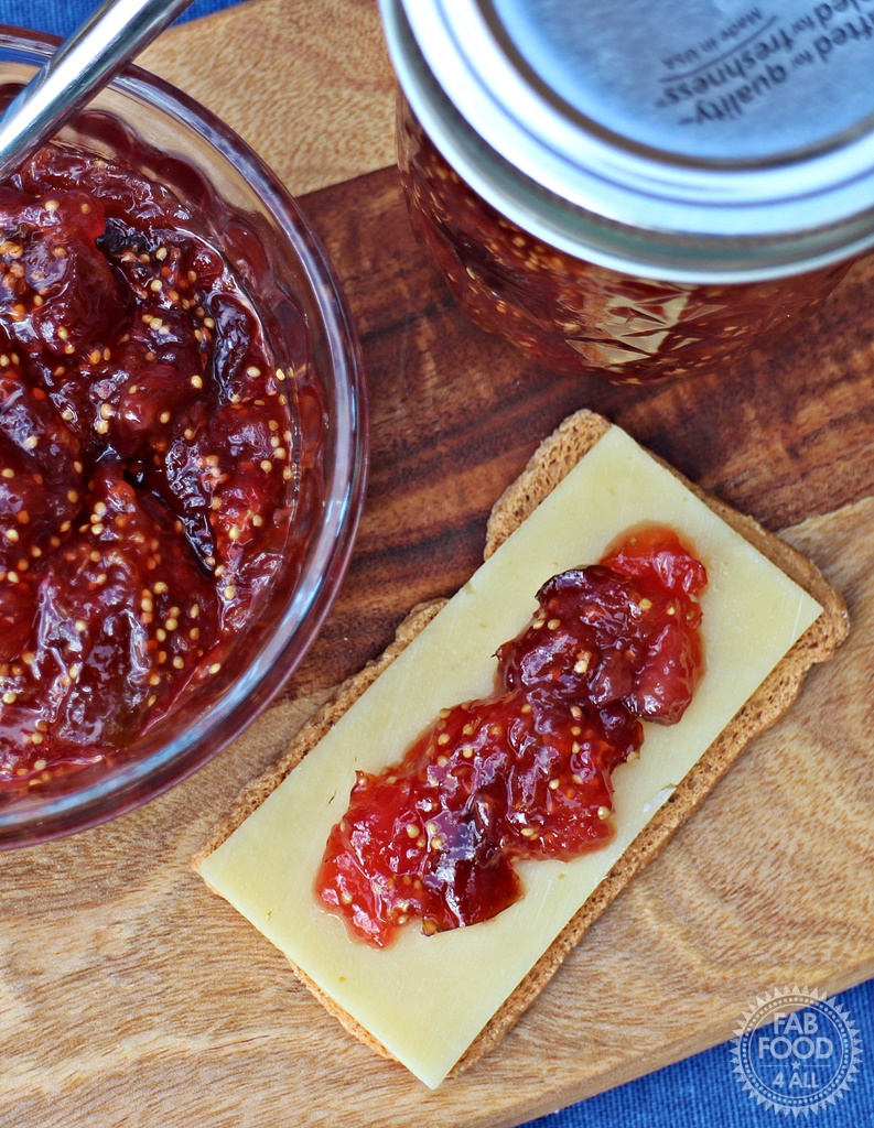 Simple Fig Jam with cheese on a cracker next to dish & jar (overhead shot)