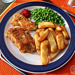 Fish and Chips with peas and tomato ketchup on a plate.