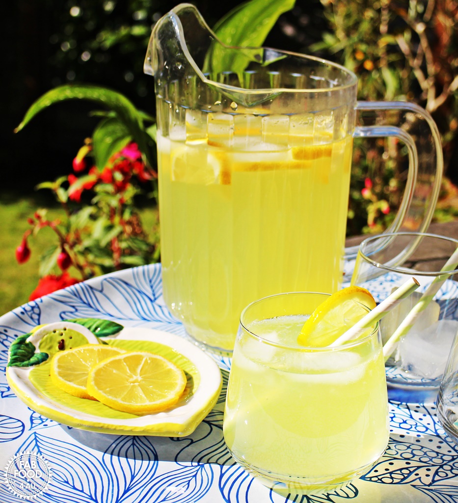 Old Fashioned Lemonade in a jug and glass on tray in garden.