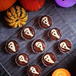 Easy Halloween Ghost Cupcakes - delicious chocolate & coffee flavoured sponge topped with chocolate spread & a handmade white chocolate ghost. Ghost, candle and pumpkin background.
