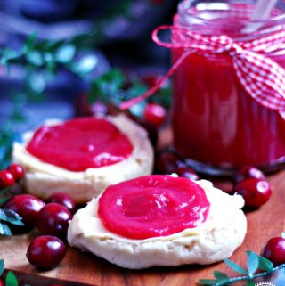 Easy Cranberry Curd spread on 2 scone halves with jar in background.