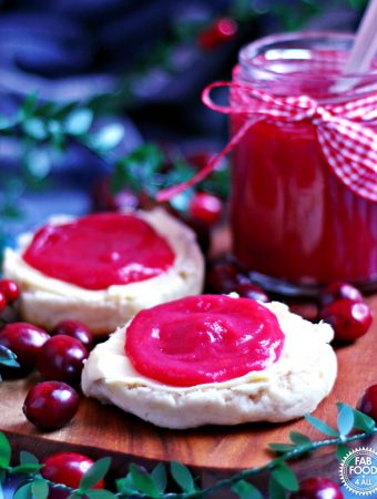 Easy Cranberry Curd spread on 2 scone halves with jar in background.