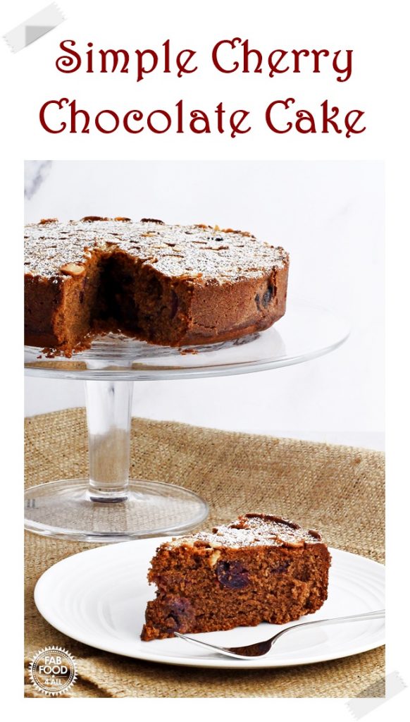 Simple Cherry Chocolate Cake on a glass pedestal with silver cake server. Pinterest image.