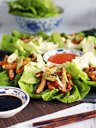 Korean BBQ Style Spicy Pork Lettuce Wraps - stripes of marinated pork on lettuce leaves, garnished with spring onion & served with sweet chilli sauce and soy sauce.