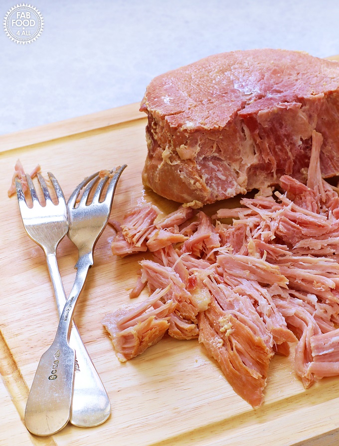 2 Ingredient Pulled Slow Cooker Gammon (Shredded Ham) on a board. with 2 forks