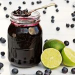 Blueberry & Lime Jam in a jar surrounded by blueberries & limes.