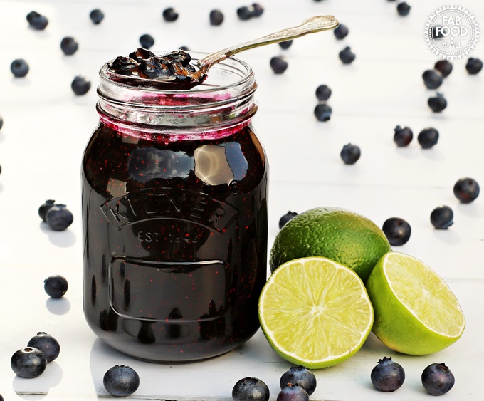 Blueberry & Lime Jam in a jar surrounded by blueberries & limes.