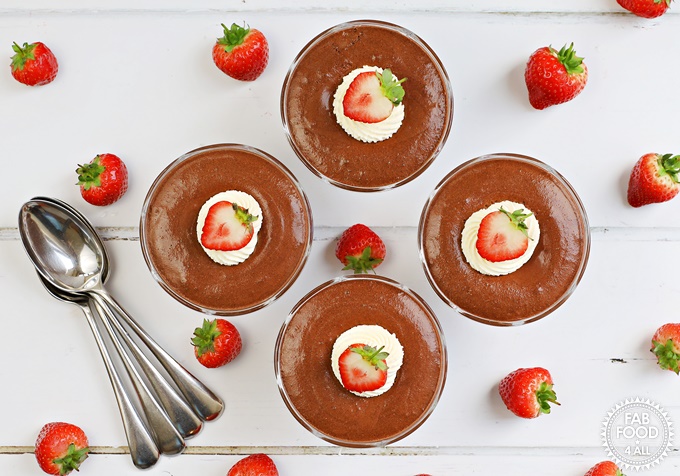 Foolproof Rich Chocolate Mousse with piped whipped cream & strawberry decoration in sundae glasses.