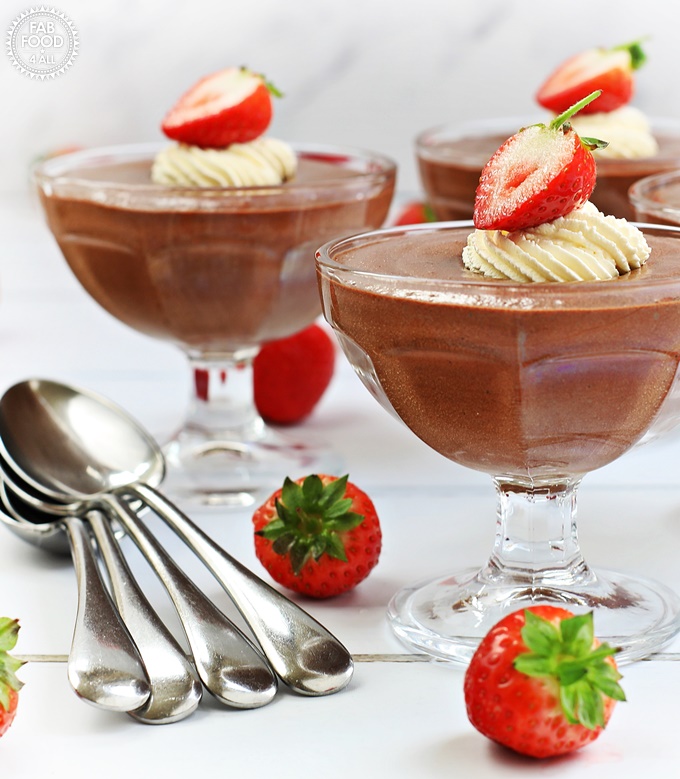 Foolproof Rich Chocolate Mousse with piped whipped cream & strawberry decoration in sundae glasses.