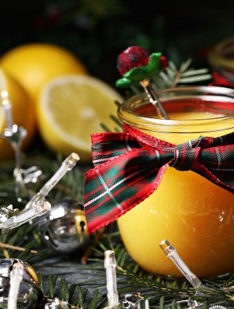 Snowball Curd in jar with tartan bow with teaspoon, lemons, Christmas tree branches & fairy lights.