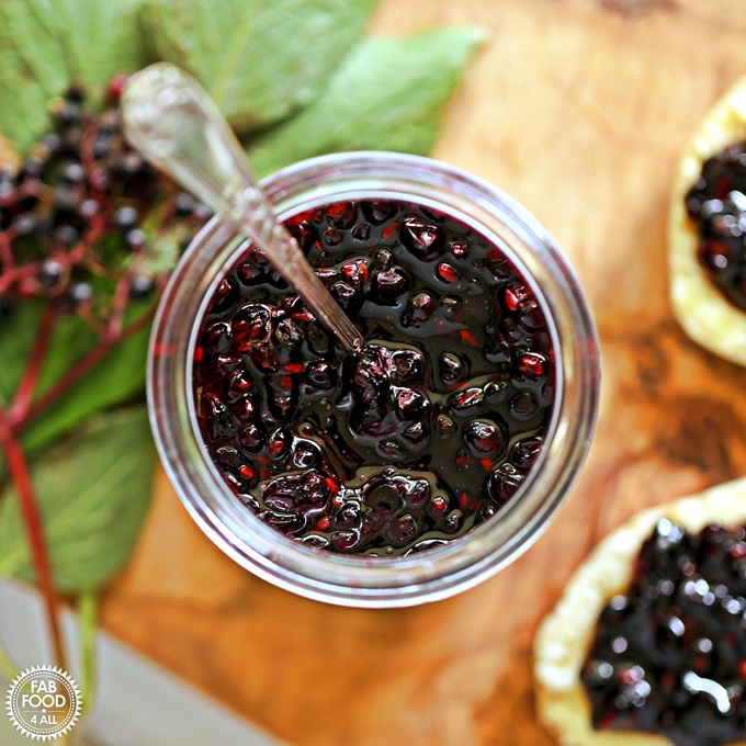 Aerial view of Elderberry Jam with teaspoon on board with scones.