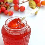 Side shot of Crab Apple Jelly in a jar with spoon resting on top.