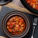 Slow Cooker Beef Stew in a bowl. with rolls & Crock Pot.