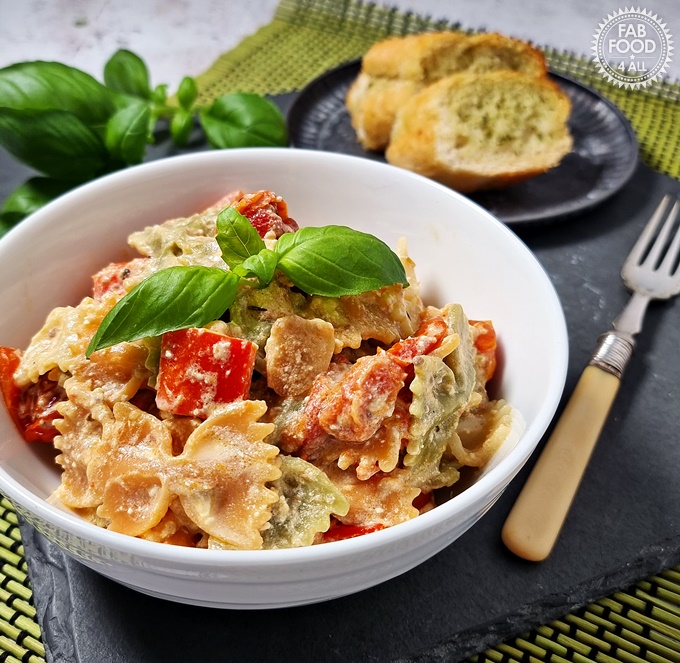 Best Baked Feta Pasta Recipe in a bowl with garlic bread in background.