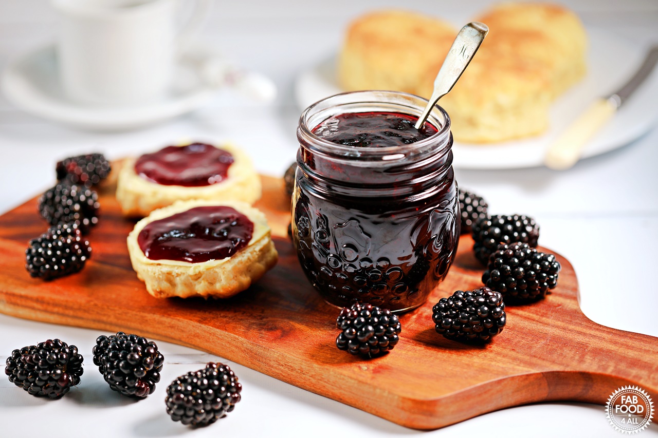 Easy Seedless Blackberry Jam with scone. and blackberries on a board.