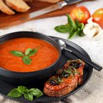 Roasted Tomato & Garlic Soup with Basil in a bowl with pizzetta toast.