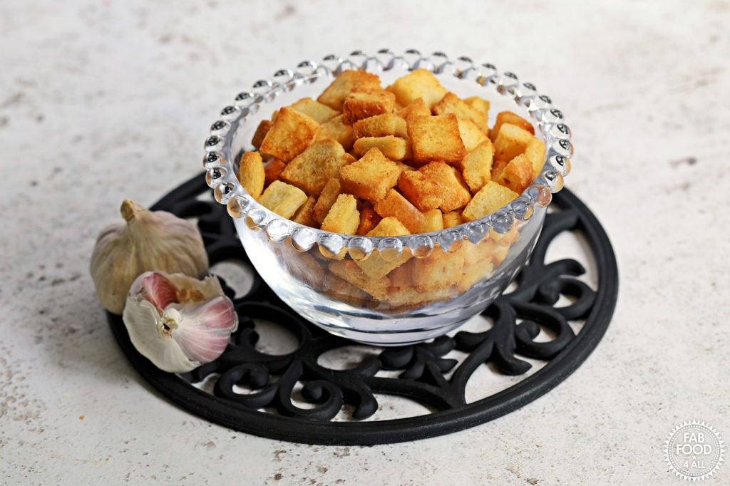 Easy Garlic Croutons in a glass bowl & 2 bulbs of garlic.