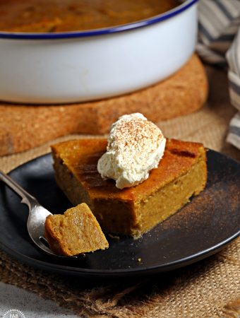 Easy Pumpkin Pie Pudding in pie dish in background and on a plate topped with whipped cream & dusting of cinnamon..