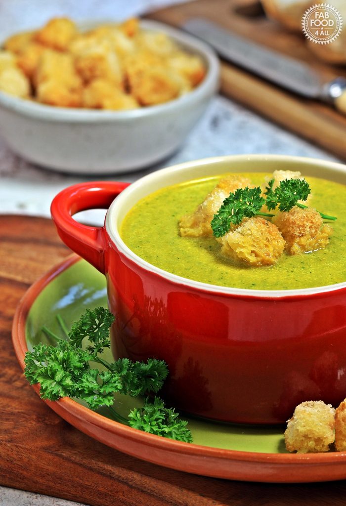 Carrot & Parsley Soup in a bowl with garlic croutons and crusty bread.