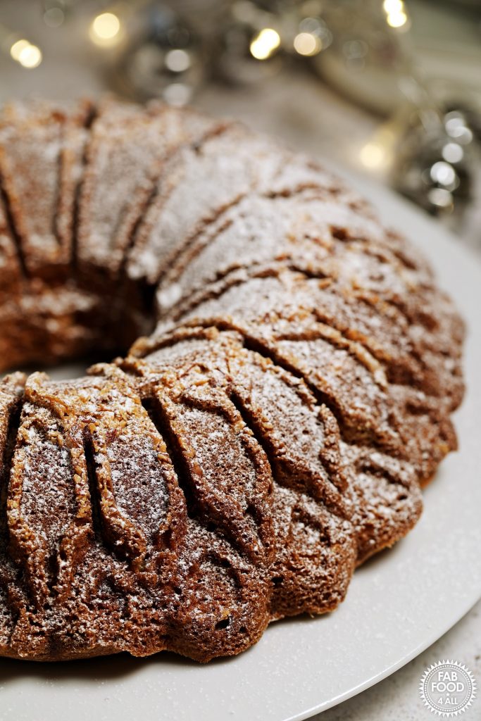Christmas Bundt Cake with Christmas lights twinkling in background.