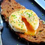 Close up of Air Fryer Baked Egg with Cheese on toast, garnished with chives.