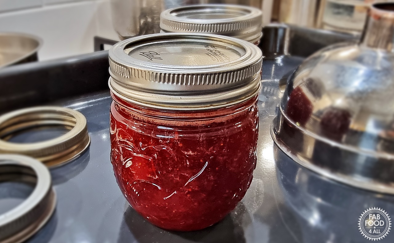 Strawberry & Gin Jam in a jars with lids and jam funnel in background.