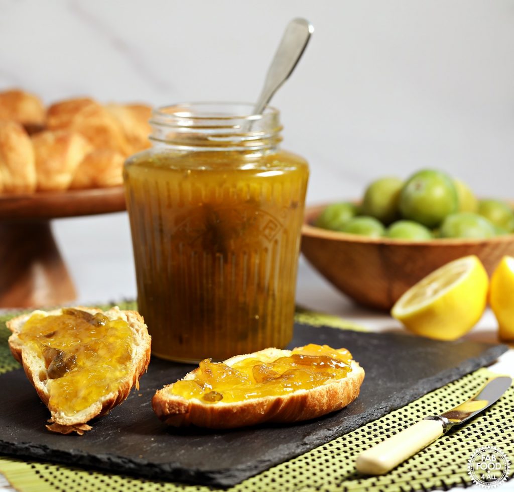Jar of Easy Greengage Jam on a slate with buttered croissant spread with jam.