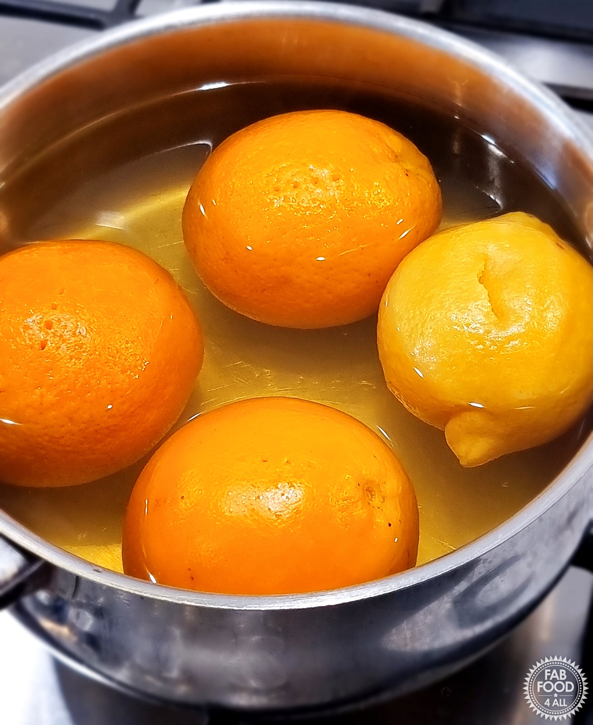3 oranges and a lemon in a pan of water that have been boiled to soften skins.