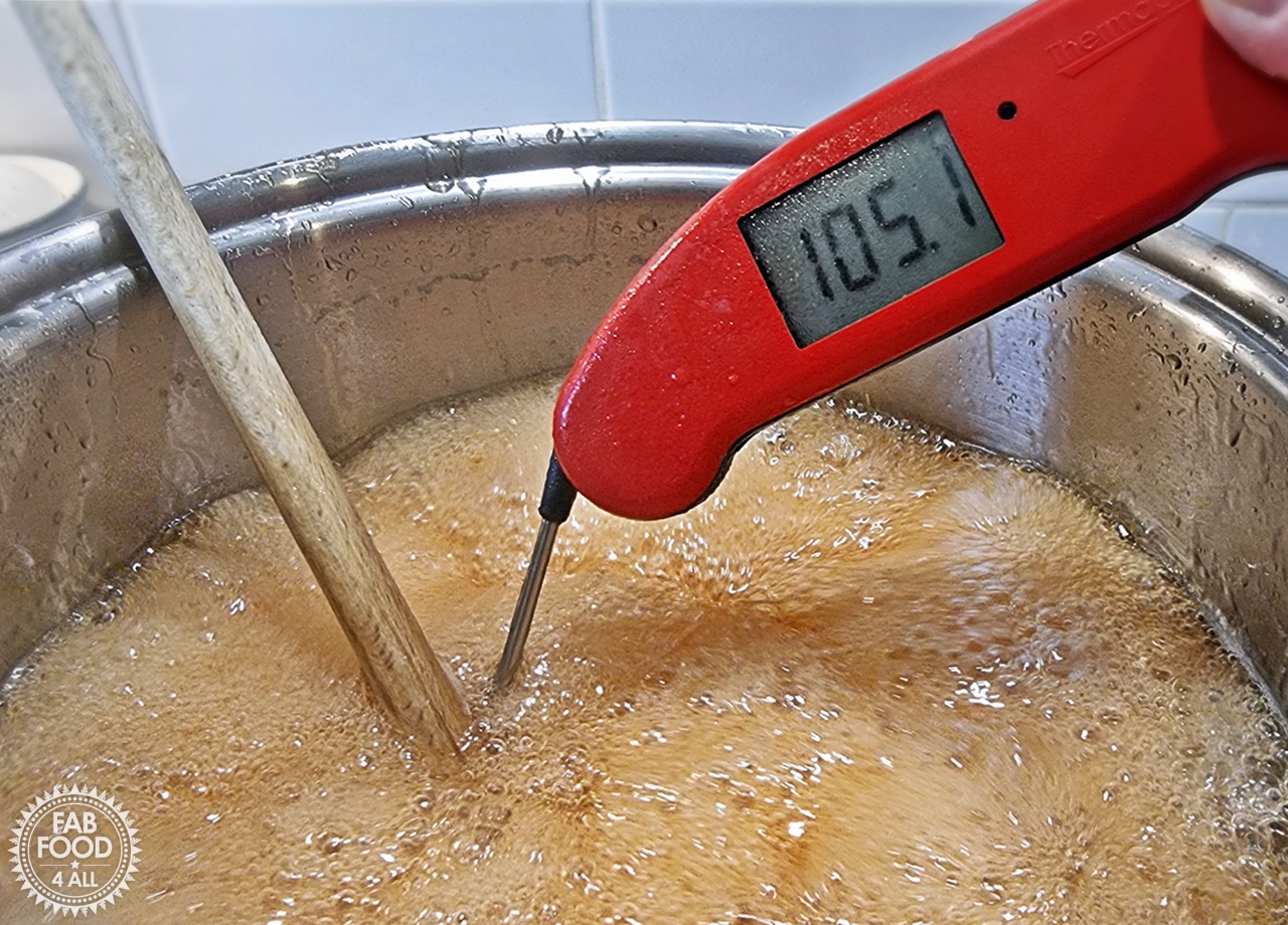 Jelly at a rolling boil with digital thermometer showing temp of 105C.