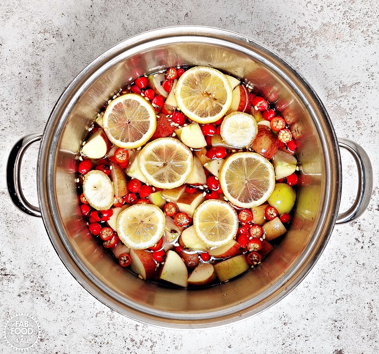 Pan with water, rosehips, apples and lemon slices.