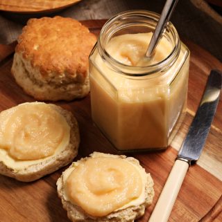Easy Quince Curd in a jar (with teaspoon) on a board with scones, knife and quince.