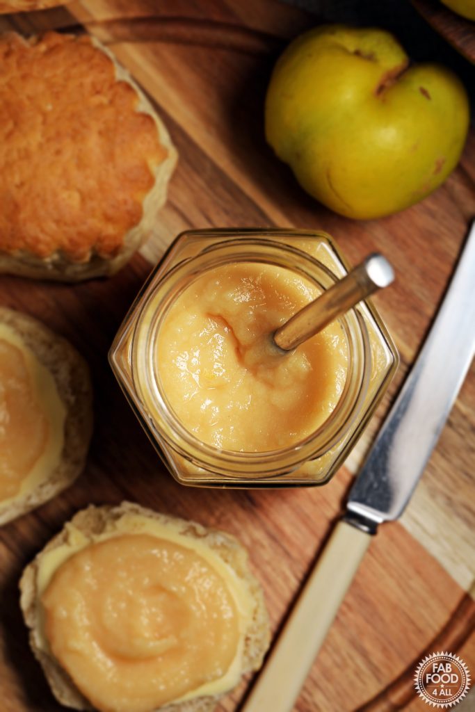 Aerial view of Easy Quince Curd in a jar on a board with scones, knife and quince.