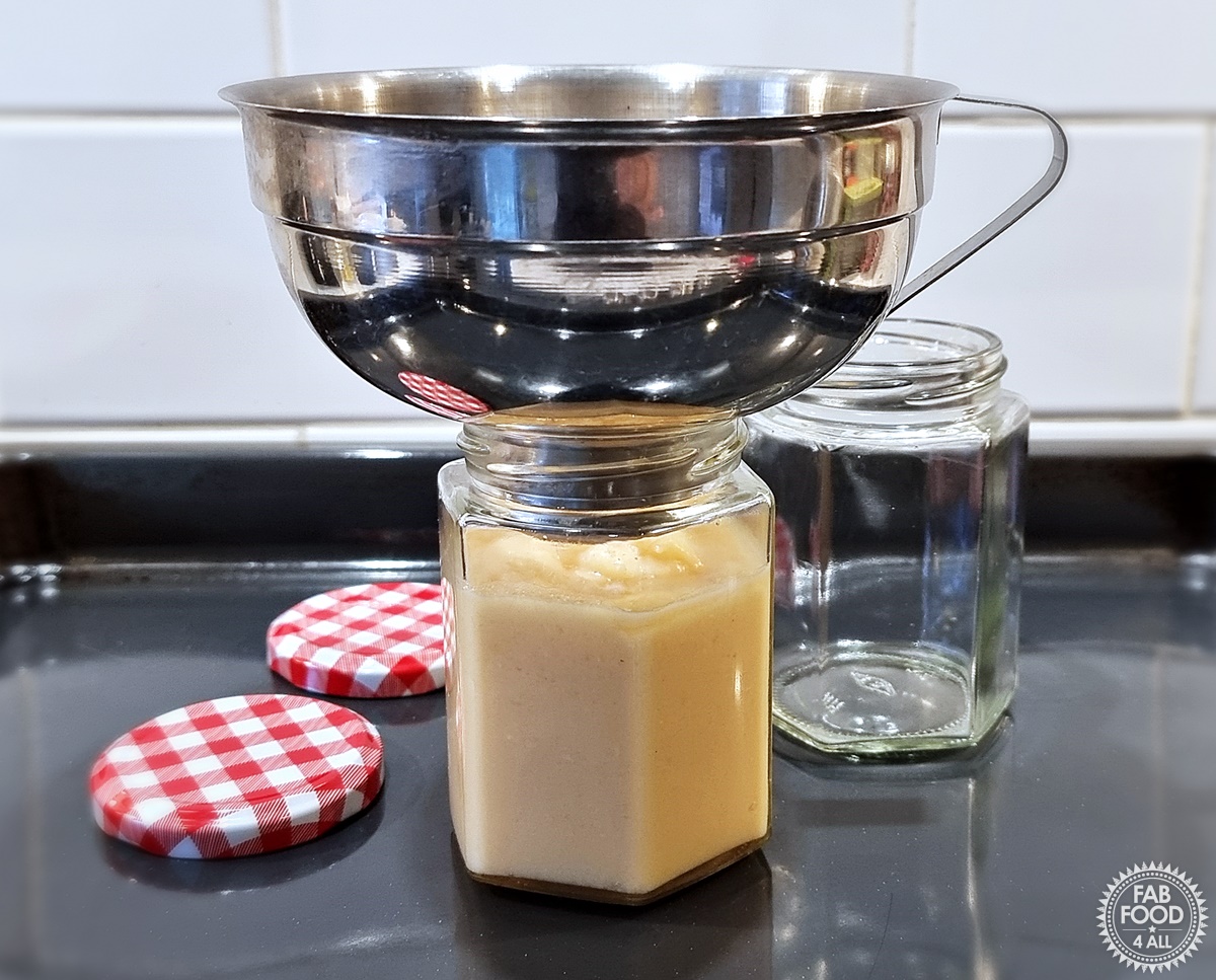 Easy Quince Curd being potted up using a jam funnel.