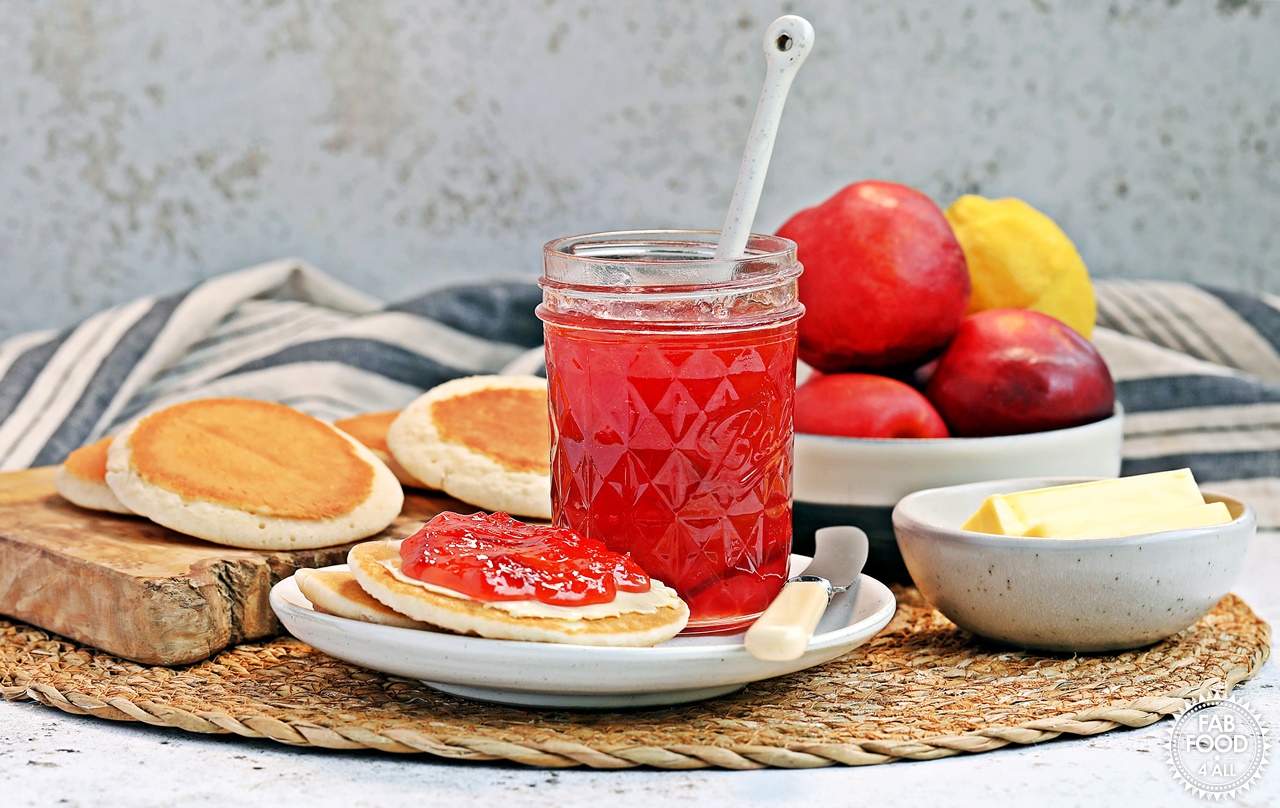 Open Easy Nectarine Jam jar on a plate with Scotch Pancakes and various props.