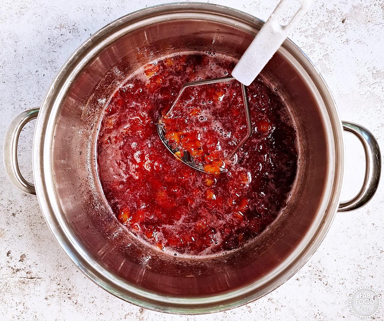 Using a potato masher to crush the nectarine chunks in the jam.