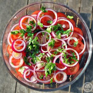 Overhead shot of glass dish of Tomato, Red Onion & Coriander Salad