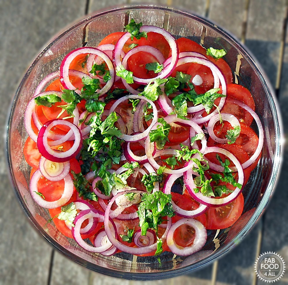 Overhead shot of glass dish of Tomato, Red Onion & Coriander Salad