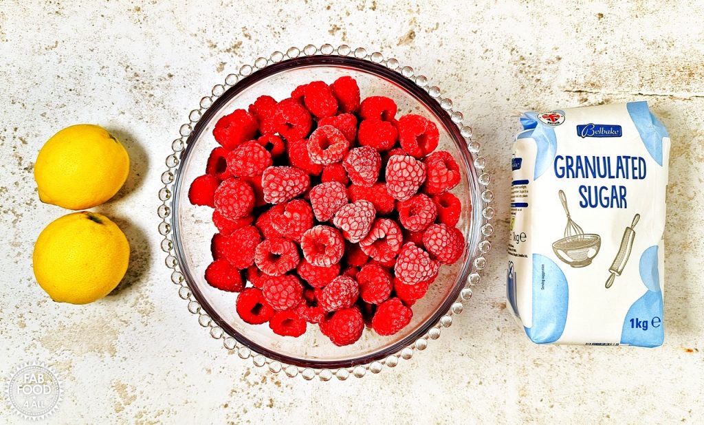 Quick & Easy Raspberry Jam Recipe Ingredients: 2 lemons, bowl of raspberries and a bag of granulated sugar.