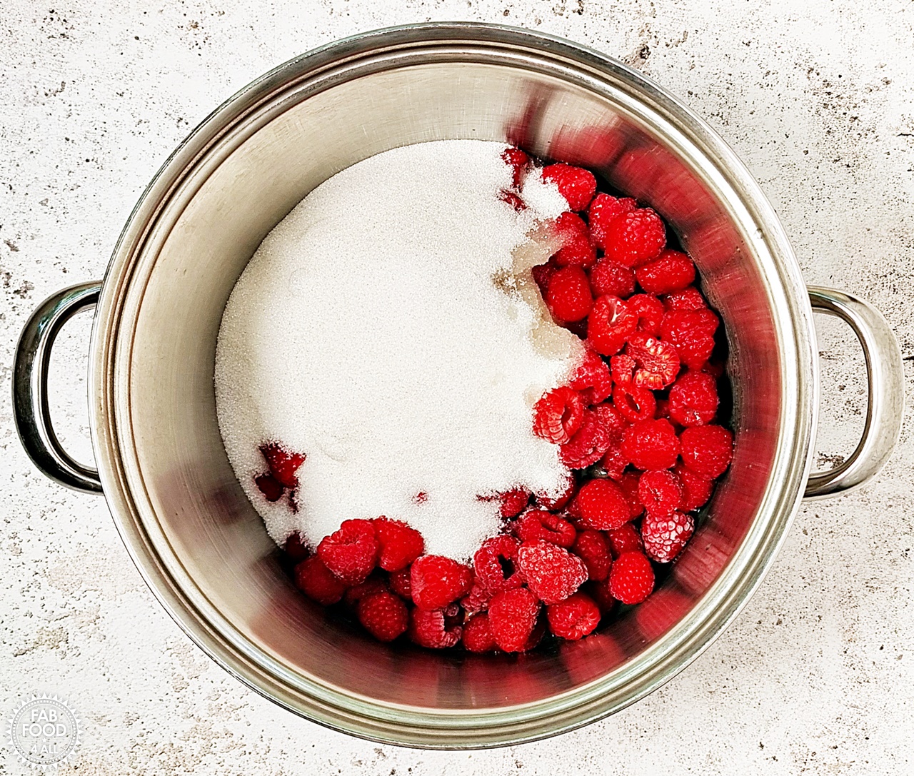 Raspberries, granulated sugar and lemon juice in a large, deep stainless steel pan.