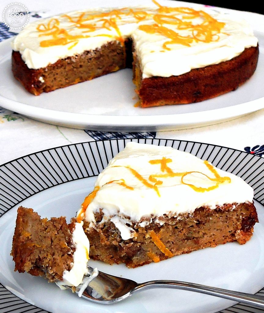 Quick & Easy Spelt Butternut Squash Cake with orange cream cheese frosting decorated in orange skin shavings on a white serving dish with slice on a plate with a laden fork in the foreground.